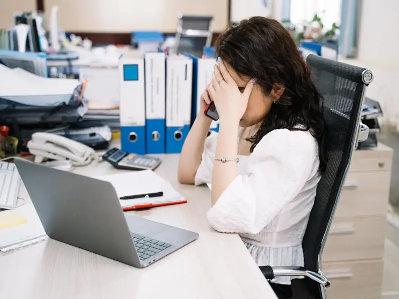 Stressed woman on mobile phone in front of laptop.